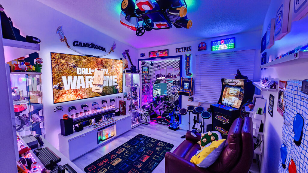 Fully equipped gamer room designed by JoystickRoom.com featuring Mario Kart, Warzone, Call of Duty, HeroBand themes, gaming consoles, LED lighting, and immersive setup
